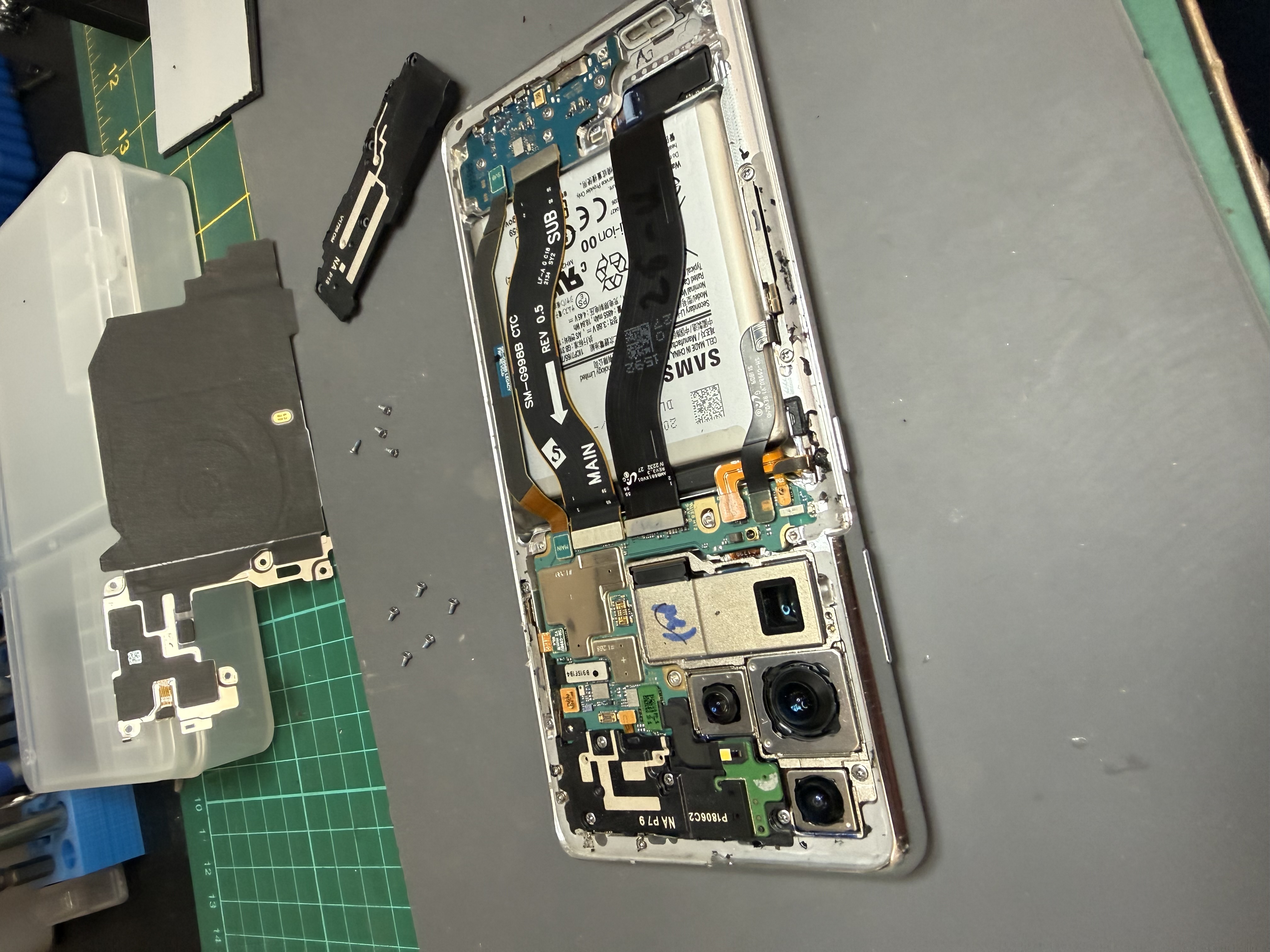 Samsung Galaxy phone opened with main board, cameras and ribbon cables visible